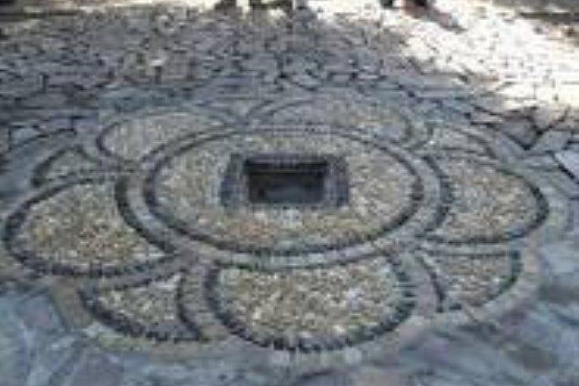 Fiore in ciotoli Ticino misti, con cornice in ciotolini color nero, contornato di cubetti 4/6 in porfido colori misti